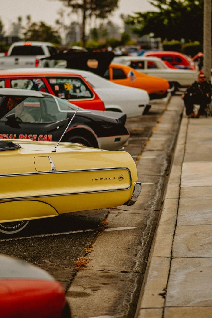 Vintage cars parked outdoors at a car meet, showcasing retro designs and vibrant colors.